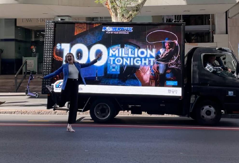 Anna Hobdell, The Lott spokesperson poses in front of a truck that reads 'Powerball $100 million tonight'. Picture supplied