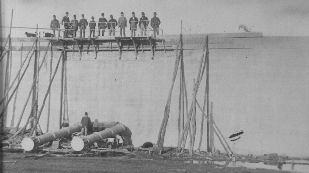 Several men stand on the top of the dam wall at Gosling Creek Reservoir as it nears completion. Picture courtesy of Central West Libraries. 