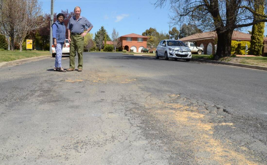 GONE TO POT(HOLES): Charles and Hawa Wright near a section of road they want council to repair. Reader Bruce Haigh says many roads in the city are in need of repair.