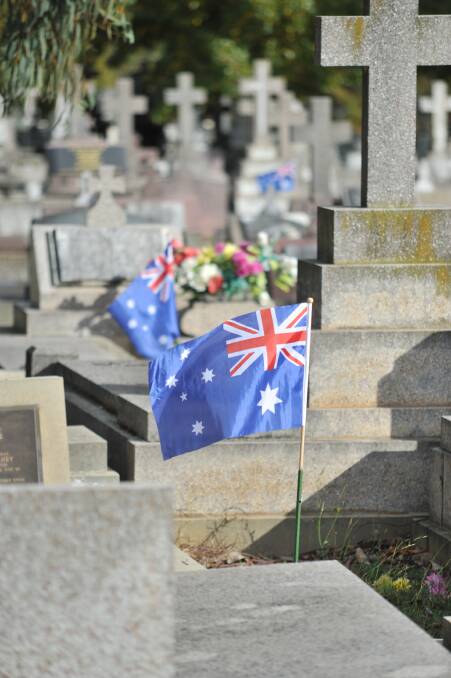 TRIBUTE: An Australian marks the grave of a serviceman. Photo: JUDE KEOGH 0425jklonepine14