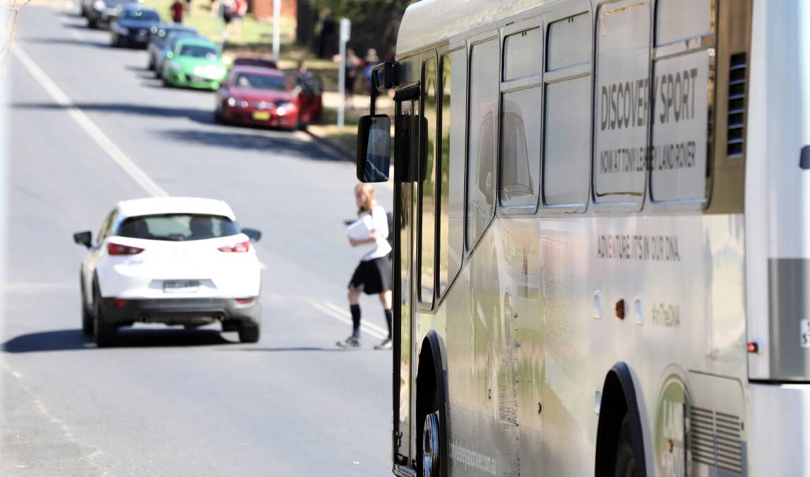 NO CROSSING: A James Sheahan Catholic High School student crosses the road between a car and a bus on Tuesday. Photo: ANDREW MURRAY
