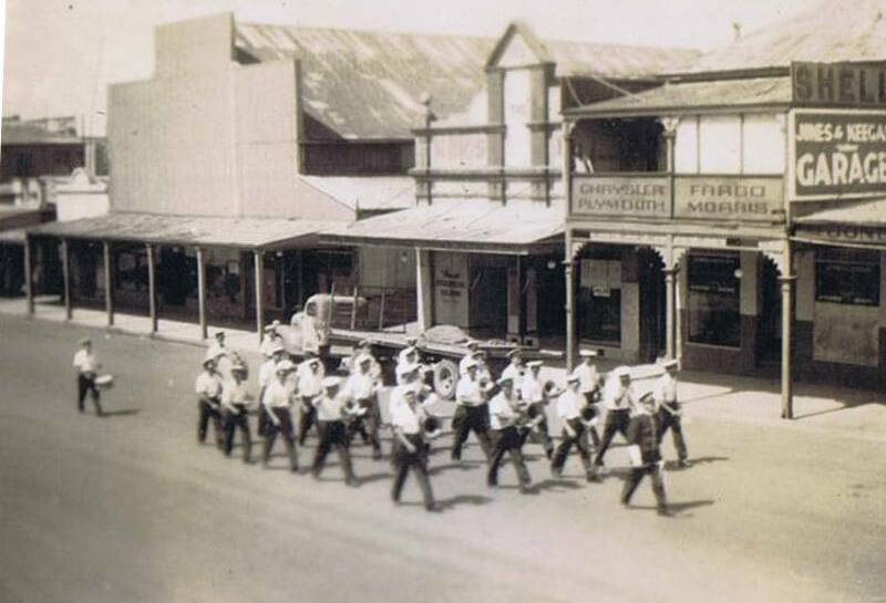 MARCHING ON: A band marches down Peisley Street from Summer Street passing a row of shops in 1947. Photo: ORANGE AND DISTRICT HISTORICAL SOCIETY