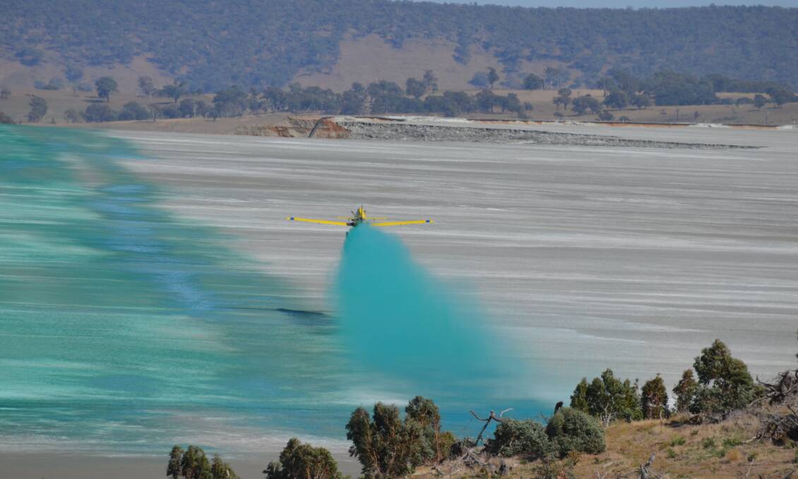 BLUE VIEW: One of the four aircraft in use spreads dust suppressant coloured with dye for identification over one of the dried-up Cadia mine tailings dams. Photo: Supplied