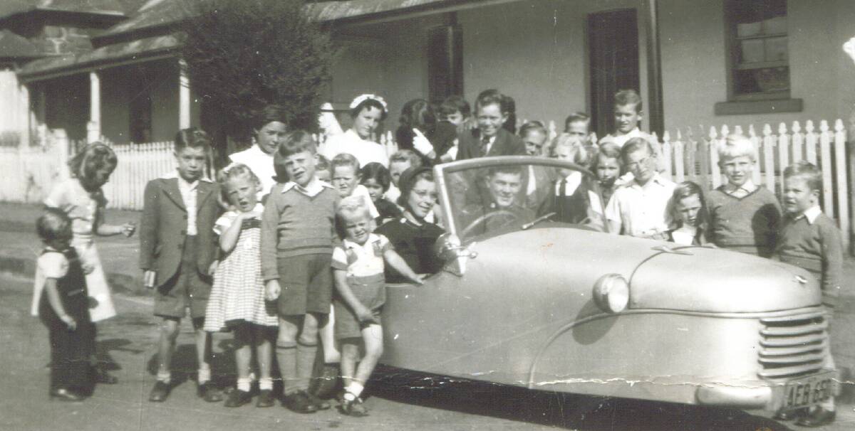 BACK THEN: Olive Griffin in her three-wheeled British-built Bond car in Kite Street surrounded by children in the early 1950s. Photo: Supplied
