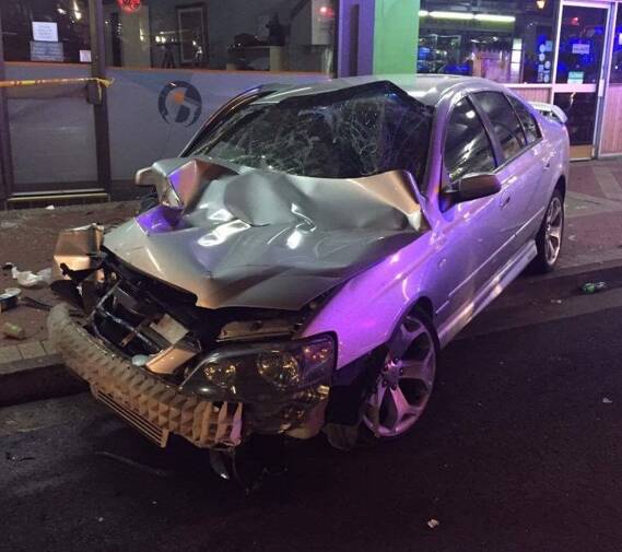 CRASH SCENE: The damaged silver Ford Falcon sits on the footpath in Summer Street on Sunday night.
