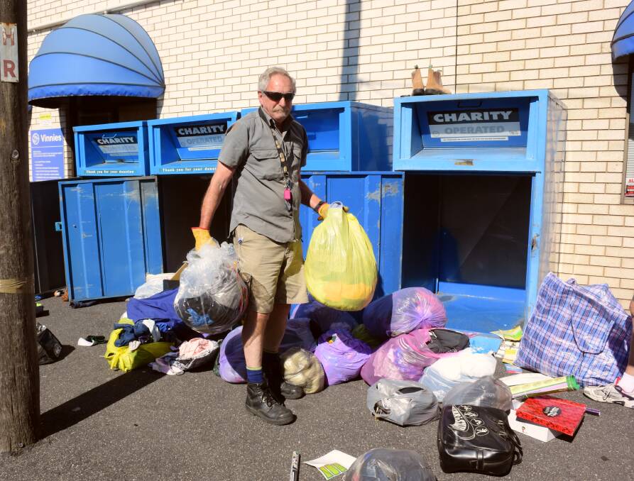 EXCESS: Vinnies volunteer Roger Anderson helps clean up bags of clothing and rubbish left at the charity's bins. Photo: DAVID FITZSIMONS 1211dfvinn1