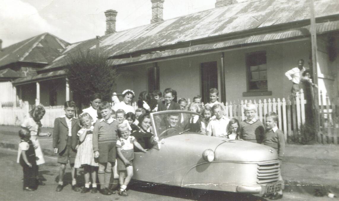 RETRO RIDE: Olive Griffin at the wheel of a unique car surrounded by children in Kite Street in the 1940s. Photo: ORANGE AND DISTRICT HISTORICAL SOCIETY