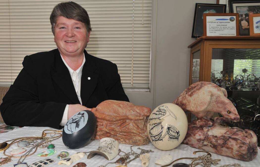 HAND CRAFTED: Kathy Selwood with some of her carvings, scrimshawed emu and ostrich eggs and jewellery. Photo: JUDE KEOGH 0123jkkathy1