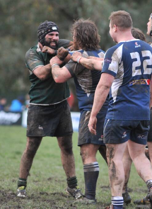 COME ON: Tom Goolagong and Jarrod Hall share pleasantries in the mud. Photo: JUDE KEOGH