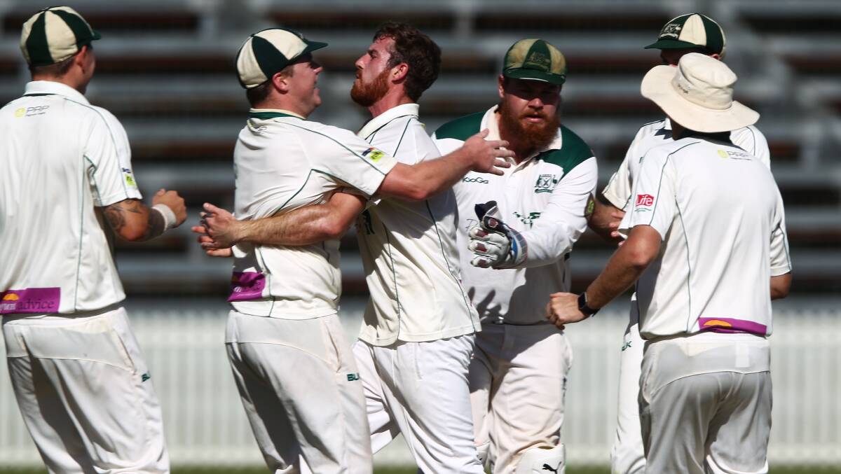 GET AROUND ME: Warriors seamer Brodie Cox is mobbed after taking a wicket in a thrilling preliminary final with Cavaliers. Photo: PHIL BLATCH