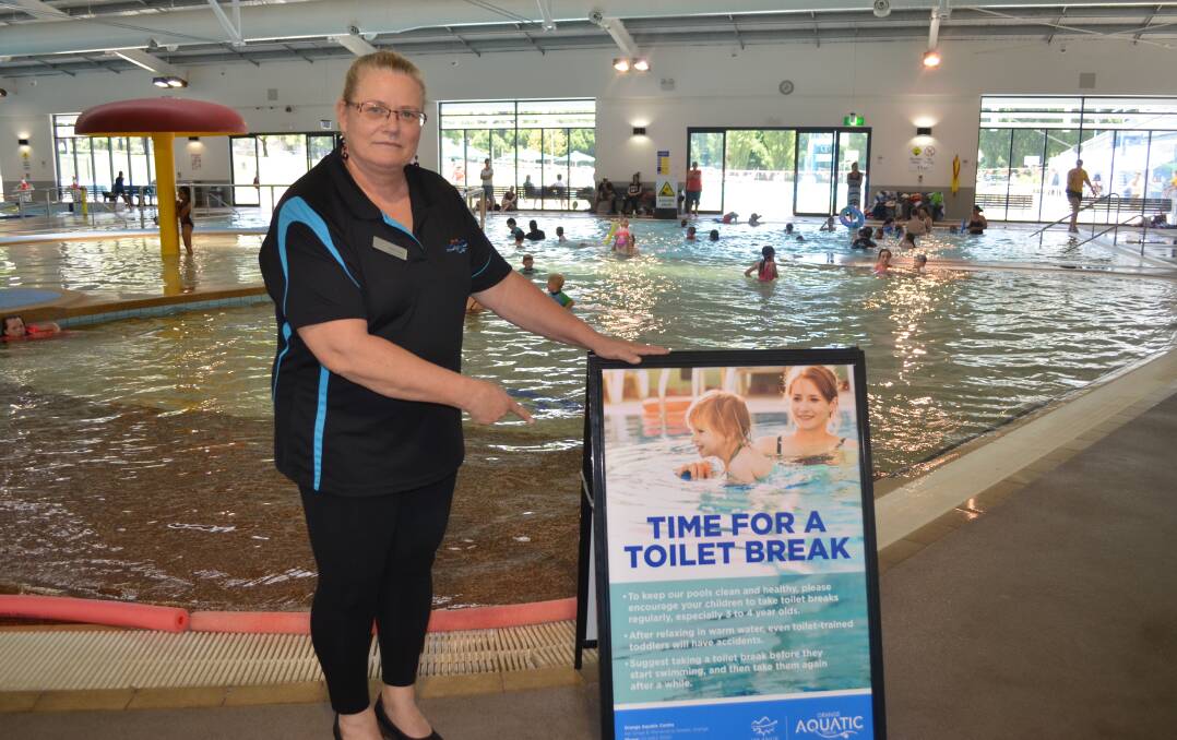 LATEST STRATEGY: Orange Aquatic Centre manager Beth Shea with one of the new signs that are being displayed in an effort to reduce closures of the pools. Photo: TANYA MARSCHKE
