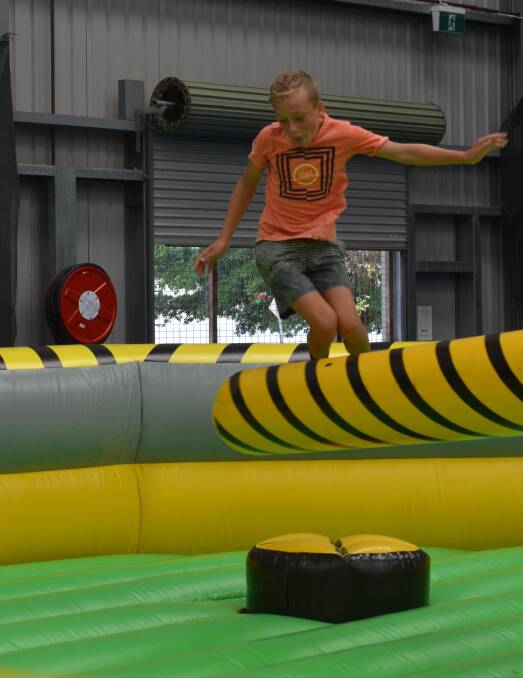 JUMP: Matthew Kacarouski leaps over a rotating, inflatable beam at the Jump Inflatables playground at the indoor tennis courts. 0112tmjump1