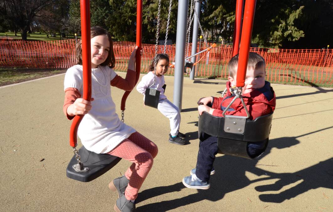 SWING SET: Orange children Eloise Thurlby, Mahalia Edwards and Lorcan Thurlby playing on the new play equipment at Cook Park last month. Photo: JUDE KEOGH