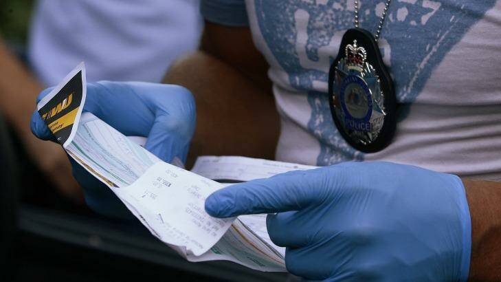 A police officer takes a Western Union money transfer receipt from a car outside Tamim Khaja's home. Photo: Daniel Munoz