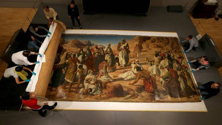 Conservators and volunteers carefully roll out a large-scale John Herbert painting at the National Gallery of Victoria. Photo: Wayne Taylor