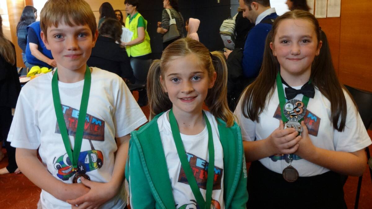 Team members Charlie Southwell, Kaitlin Borkowski and Caitlyn White with green ribbon and medal around their neck.