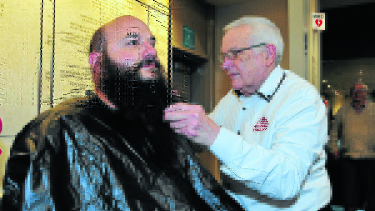 A CLOSE SHAVE: Barber Lindsay Totman shaves off John Giameos’ beard to raise money for the McGrath Foundation last Tuesday. Photos: LUKE SCHUYLER  0506lsshave4