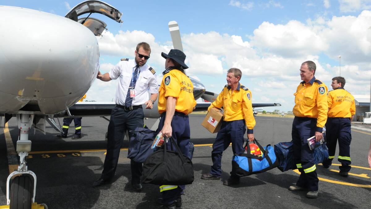 READY TO BOARD: Pilot Jesse Dargan boards Craig Petersen, Rodney Oxley, Ian Wotton, and Mark Gray. The rural firefighters are heading to South Australia to help battle blazes in the Adelaide Hills. Photo: JUDE KEOGH