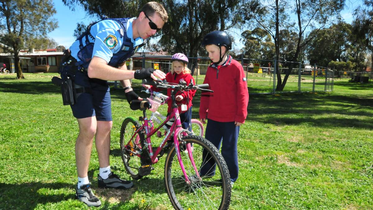SAFETY SESSION: Senior Constable Chris Tomlinson gives Charlotte Harper and Pavlik Pasishnichenko some bike safety tips at Bowen Public School on Thursday. Photo: JUDE KEOGH                                          0918bowenbikes1
