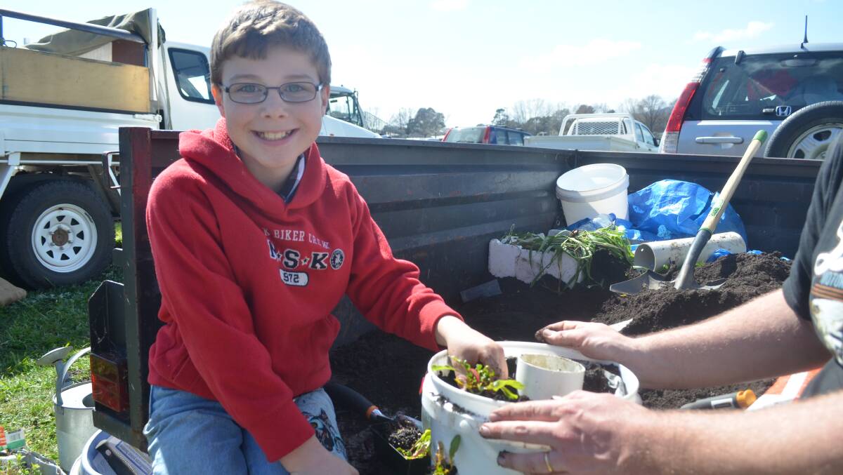 GREEN THUMBS: Nine-year-old Orange boy Caleb Parker gets his hands dirty planting vegetables in his own worm tower garden at Orange Region Farmers Market on Saturday. Photo: ALEXANDRA KING         0913aksustain3
