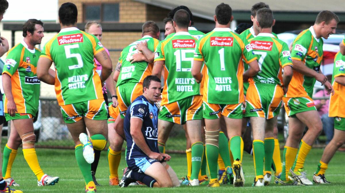 ORANGE CYMS: The green and golds celebrate another try as a despondent Hawks skipper Tim Mortimer looks on. Photo: STEVE GOSCH