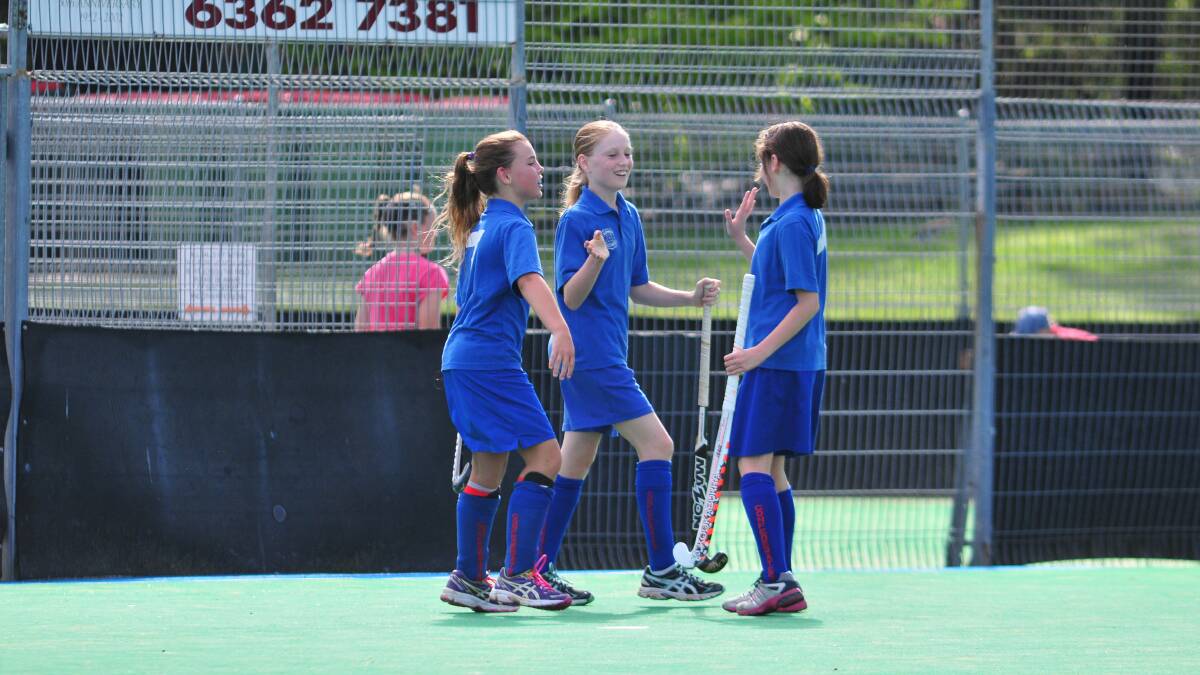 HOCKEY: Keely Middleton and Indianna Jones congratulate Isabelle Howarth on a goal on Saturday morning. Photo: JUDE KEOGH