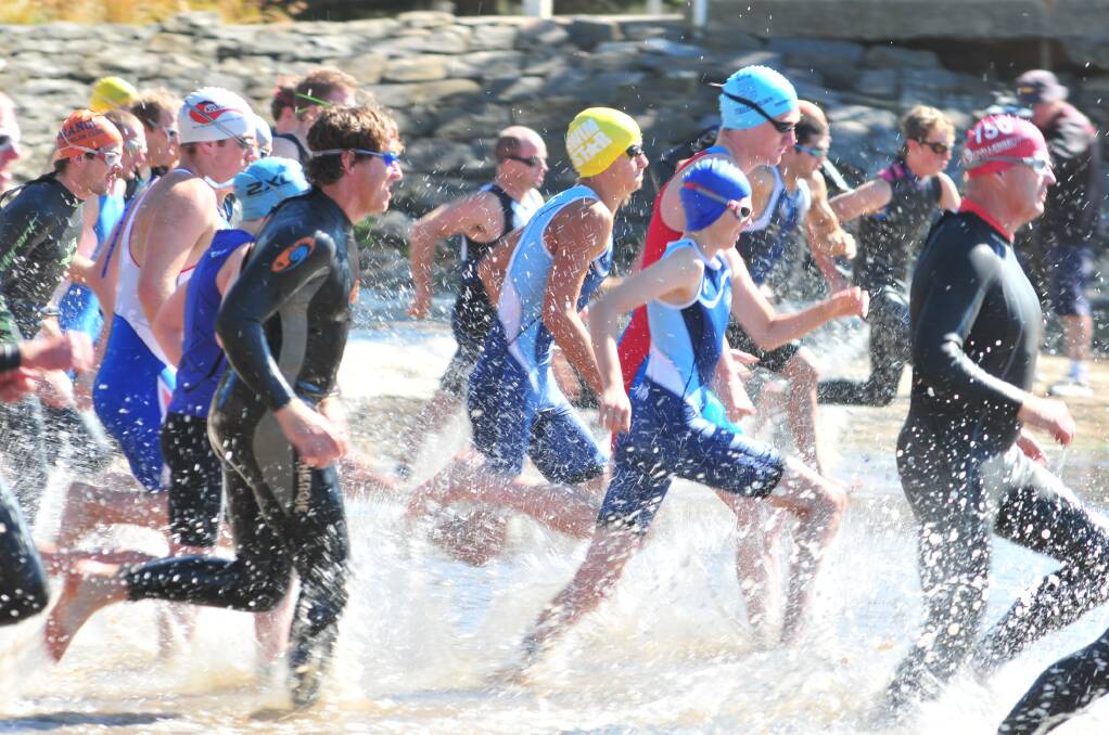 The triathletes race into the water to start the swim leg at Lake Canobolas on Sunday. Photo: JUDE KEOGH