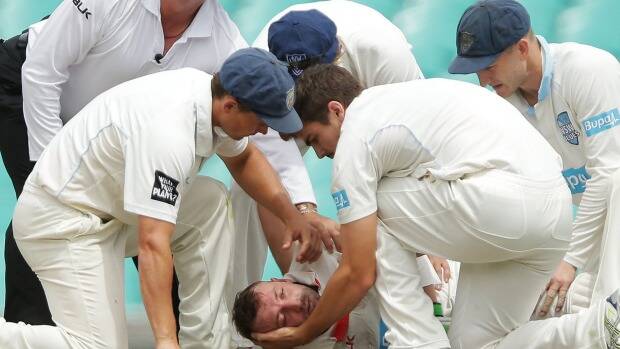 SHOCKING BLOW: Phil Hughes is cradled to the SCG ground by his NSW Blues opponents. Photo: SMH
