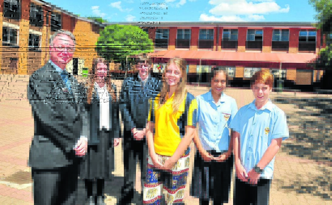 SUNNY DAYS: James Sheahan Catholic High School principal Mark Pauschman with students Eliza Harvey, Paddy Firth, Alex Wratten, Vanie Cardinio and Nicholas Brown standing proudly in front of the school building’s newly installed solar panels. Photo: JUDE KEOGH. 0224solarsheahan3