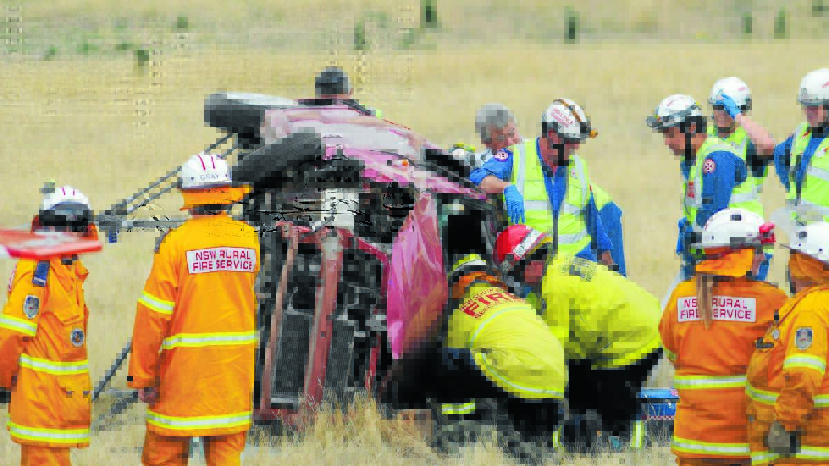 LIFESAVERS: Paramedics and firefighters rescue a 23-year-old-woman trapped in her car off Molong Road. Photo: STEVE GOSCH 0104sgcrash1
