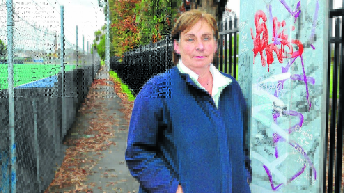 STICK IT TO THEM: Volunteer Marion Eslick hopes that graffiti in the laneway next to the hockey centre in Nunns Avenue will stop, if more Glenroi children take up hockey as a sport and grow to appreciate the centre and the people who work on it. Photo: LUKE SCHUYLER 0505lshockey