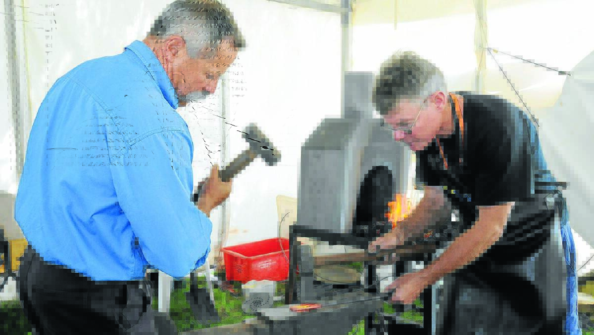 HISTORICAL TECHNIQUE: Rob Swords and Tom Miller demonstrate traditional blacksmith techniques as part of the historical farming exhibits at the Australian National Field Day yesterday. Photo: STEVE GOSCH. 1023sgfield18.