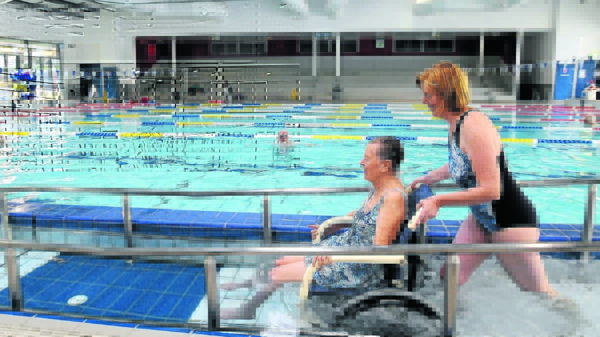 LIFE CHANGING: Ros Grant can now access the pool at Orange Aquatic Centre using a brand new $2500 water wheelchair thanks to a grant from Orange Credit Union. She’s helped by her daughter Henrietta Hood. Photo: STEVE GOSCH.  
