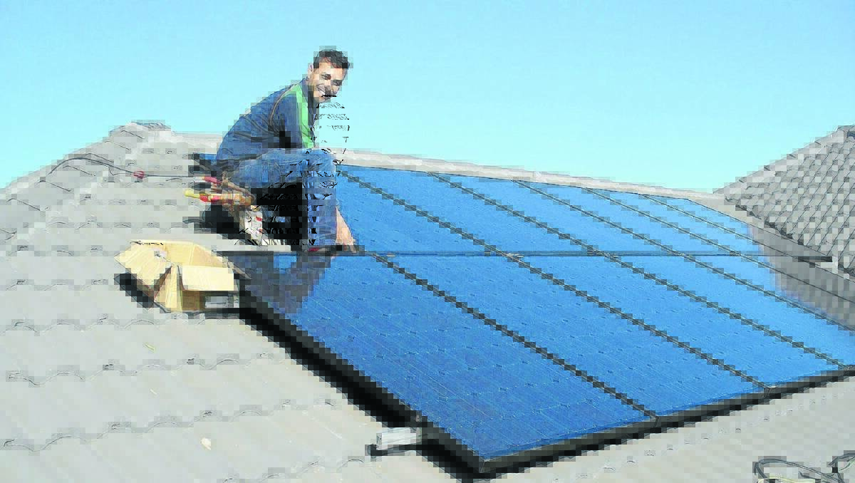 PULLING THE PLUG: Electrician Joe Fisicaro installing solar panels. A cloud hangs over the solar industry if the renewable energy target ceases.