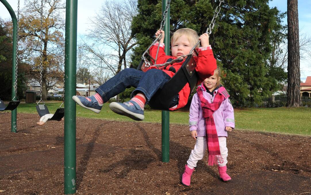 COLDER DAYS TO SWING INTO ACTION: Eleanor and Isla Fraser, from Sydney, enjoying the winter sun in Cook Park. Photo: STEVE GOSCH