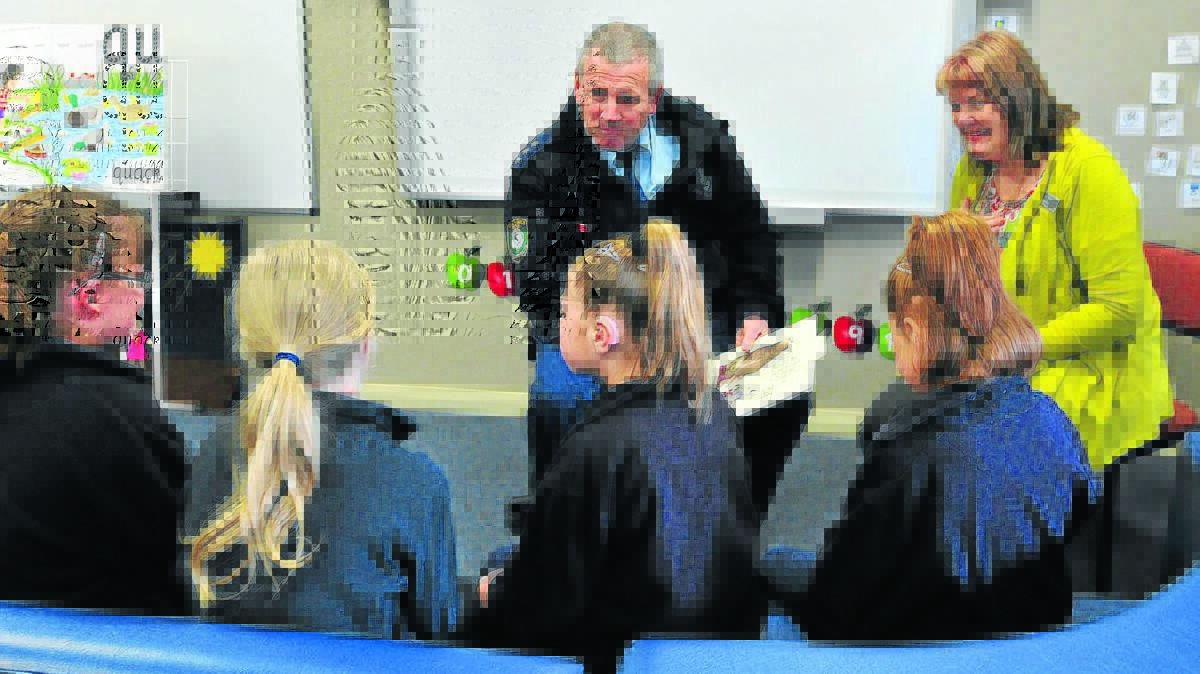 ARRESTING PERFORMANCE: Police Inspector Peter Atkins and Kathy Hayward read to students Georgie, Eleanor, Breanna and Anouk.      0822lsanson1