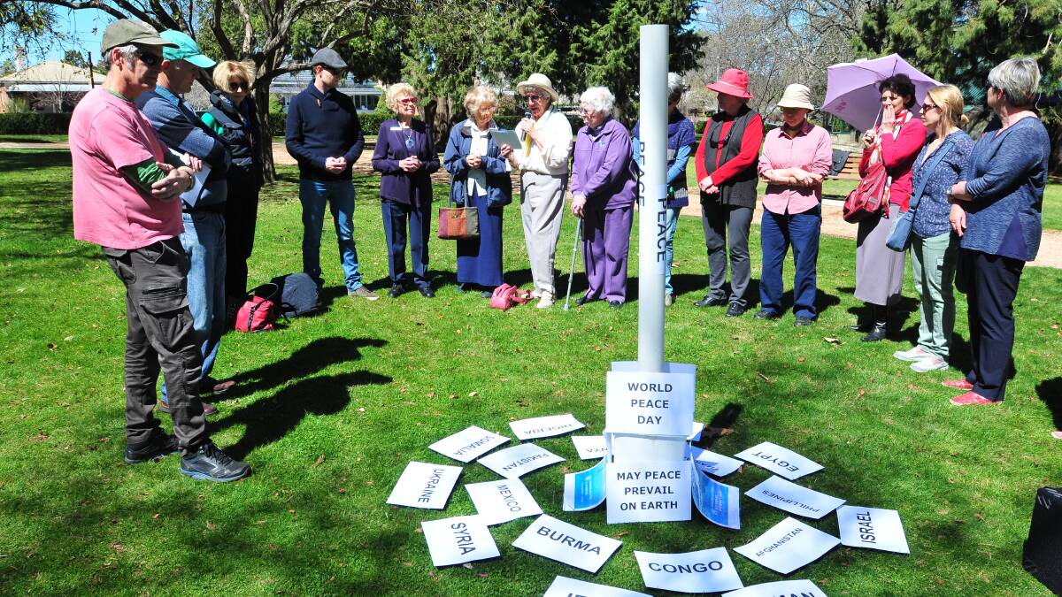 PEACE DAY: A group of Orange residents gathered in Cook Park on Sunday to mark the International Day of Peace. Bev Holland (centre) reads one of the peace offerings.  Photo: JUDE KEOGH 0921peace2