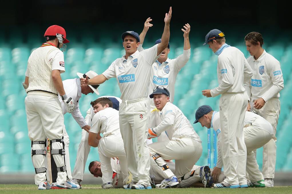 WORRIED: Players huddle around Phil Hughes during day one of the Sheffield Shield match between New South Wales and South Australia at Sydney Cricket Ground on November 25. Photos: GETTY IMAGES