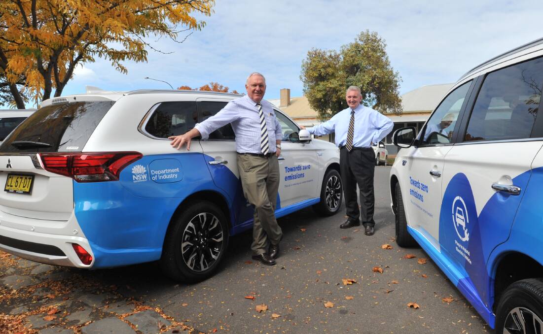 BATTERIES INCLUDED: Western NSW parliamentary secretary Rick Colless and NSW energy minister Don Harwin with the DPI's hybrid four-wheel drives. Photo: JUDE KEOGH