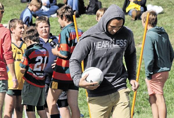 TIME PUT TO GOOD USE: Wallaby Quade Cooper shows some Orange juniors how the pros do it on Saturday.        Photos: MICHELLE COOK 0324mcquade3, 0324mcquade1