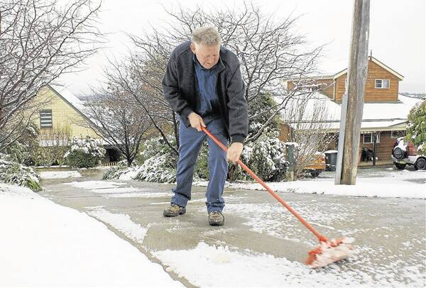 WHITE OUT: Millthorpe’s Harley Jones clears slush from his driveway. The Orange district received up to 10cm of snow on Wednesday morning.