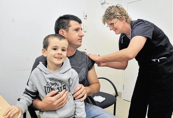 WHOOPING COUGH BOOSTER: New parent Martin Price, with son Brodie, receives a whooping cough vaccination from infection control clinical nurse specialist Sue Lovell-Smart who says immunity can waver as you get older. Photo: JUDE KEOGH 0308cough1