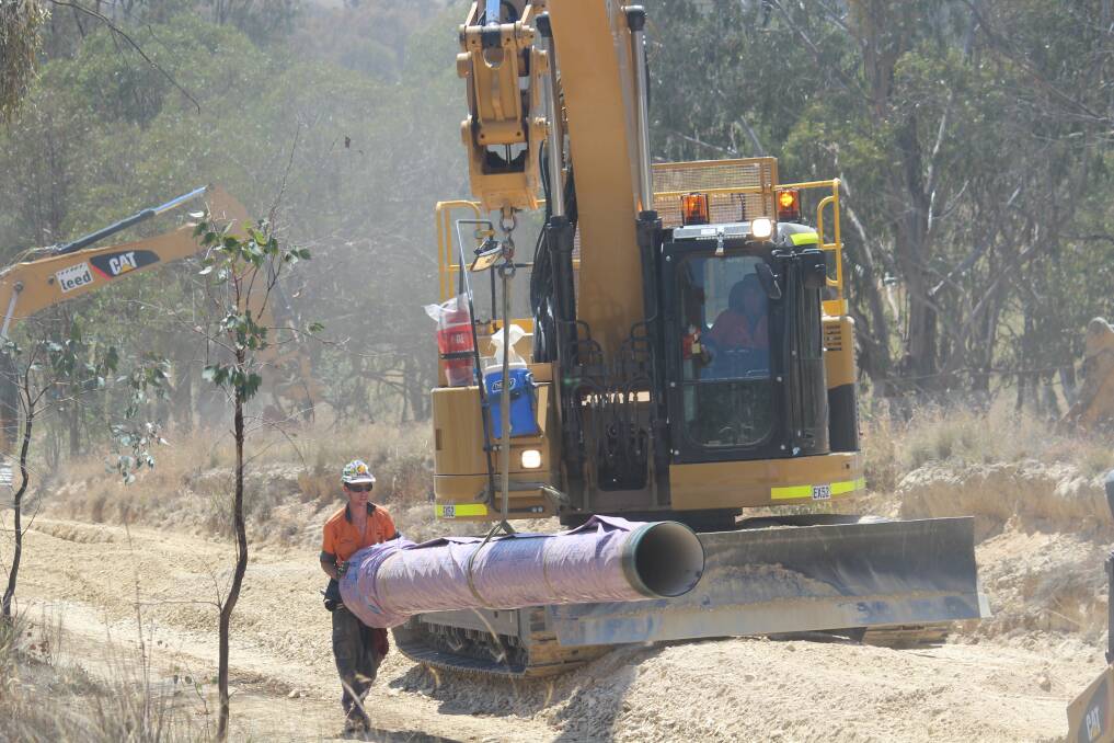 Workers lay pipe along Long Point Road. Photo: MELISE COLEMAN