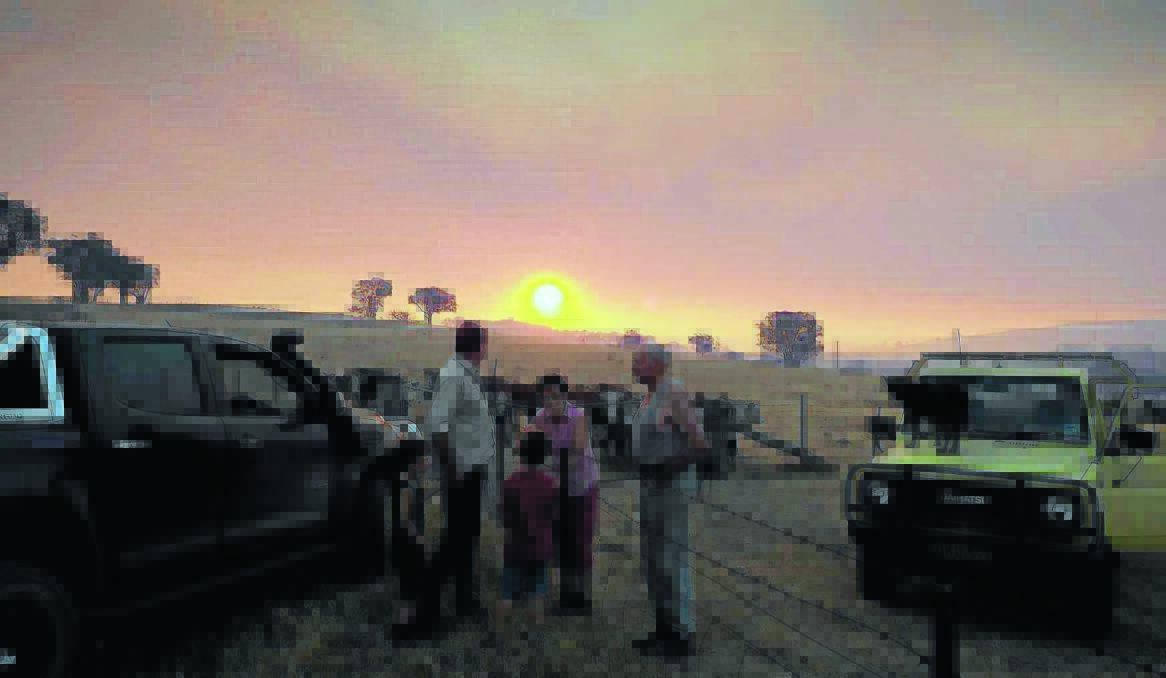 EERIE GLOW: Matt Molloy with his children Oliver, 5, and Mitchell, 7, chat with his parents on the neighbouring property Paul and Deirdre Molloy about the fire at Hells Hole. Photo: ZENIO LAPKA                    012014zneville (12)