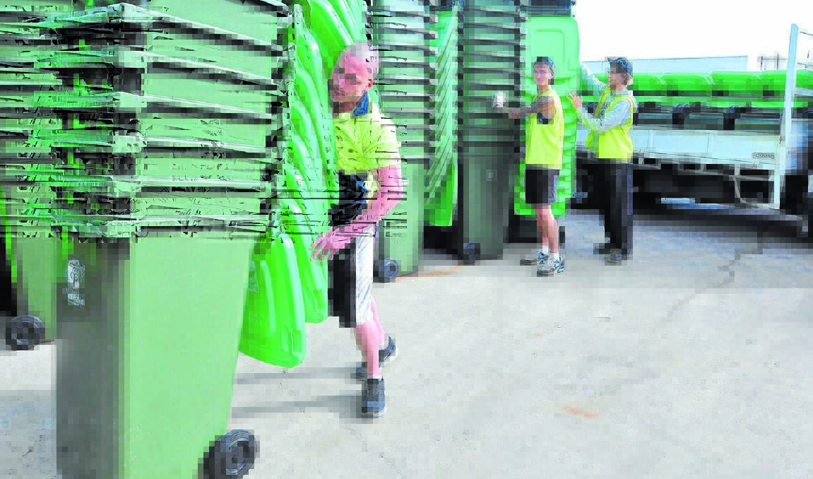 WHERE YOU BIN: Mastec employees Daniel Benson, Dylan Emery and Daniel Turner with some of the 10,000 green bins waiting to be delivered from next Monday. Photo: JUDE KEOGH 						       0501bins1