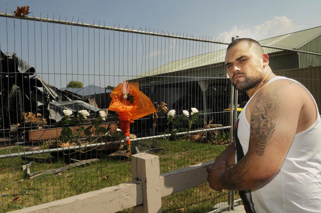 BATHURST: Kurt Lansom looks at some of the flowers that have been left for the little dogs that perished in the inferno that took hold of his mother Tracey Humphries-Gallegos’ Havannah Street home. Photo: PHILL MURRAY 011614pkurt