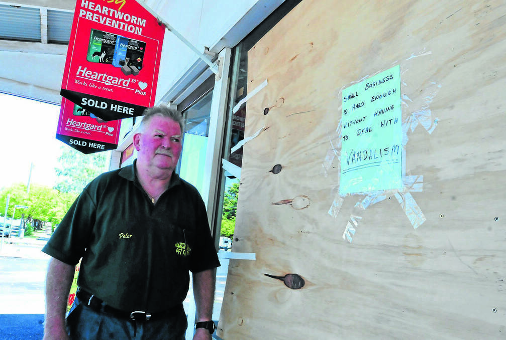 ORANGE: March Street Pet Foods owner Peter Moad posted a message for vandals who threw a beer keg through his now boarded-up front window. Photo: JUDE KEOGH 0129vandal5