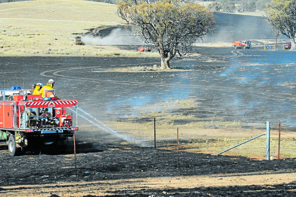 MUDGEE: Rural Fire Service crews work on the scorched ground following a grass fire on Blue Springs Road outside Gulgong.