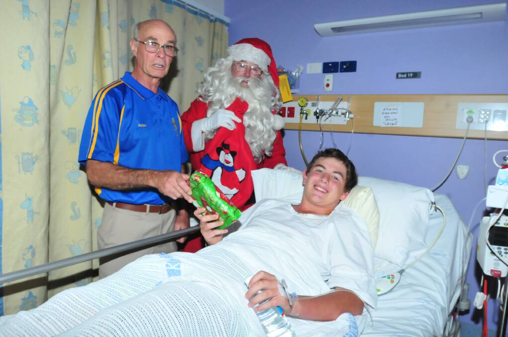 SANTA'S PRESCENCE: Lions Club member Peter Fuge helps Santa deliver presents to the children in Orange hospital over Christmas including Jason Kirkman. Photo: LUKE SCHUYLER.