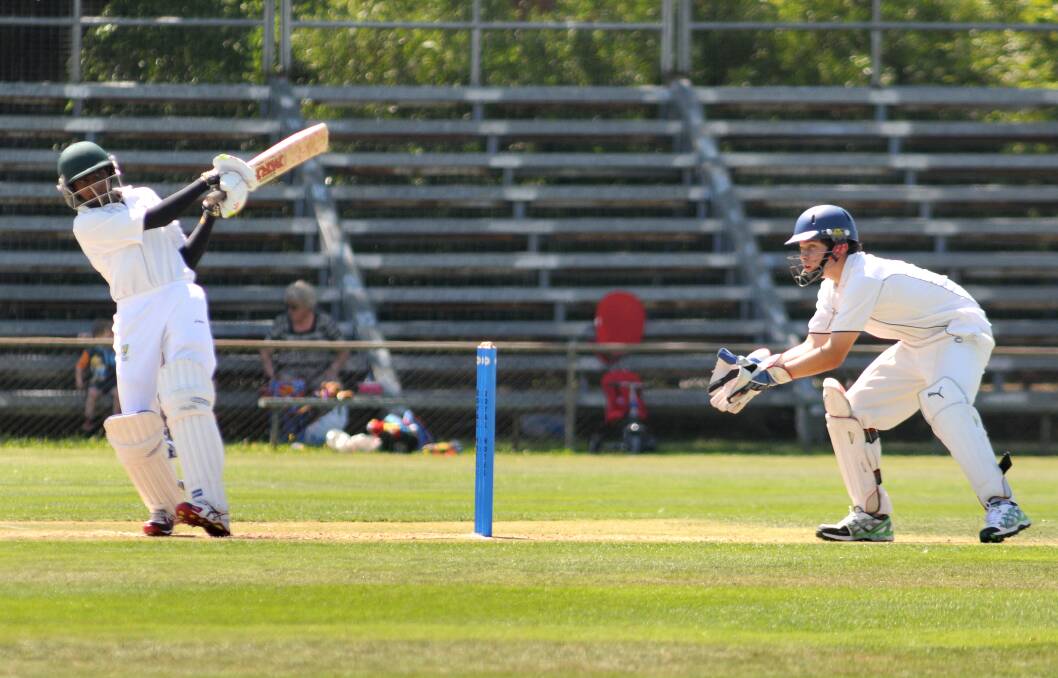 HITTING OUT: ACT under 15s star batsman Kris Weereratne and Mitchell wicketkeeper Michael Hannelly in action during yesterday's final. Photo: STEVE GOSCH 	            0116sgcrick4